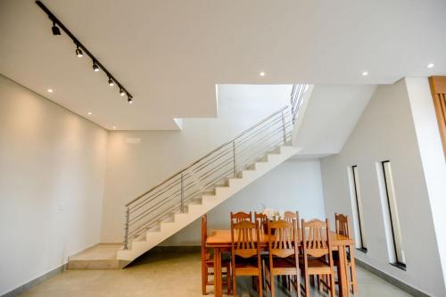a dining room with a table and a staircase at Casa com Piscina Aquecida Churrasqueira e Hidro in Franca