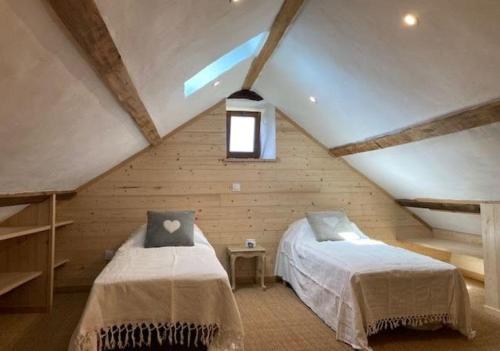 a attic bedroom with two beds and a window at Le verger in Vébron