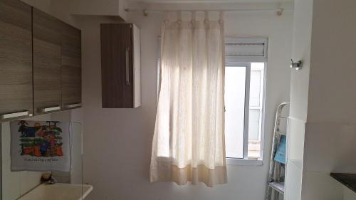 a bathroom with a white curtain and a window at Condomínio Bélgica in Presidente Prudente