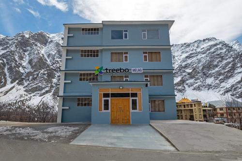 a blue building with a door in front of a mountain at Treebo Melag Jispa With Mountain View in Jispa