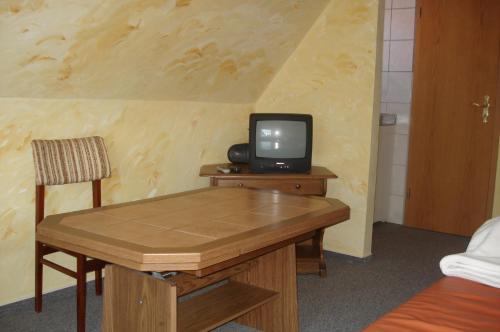 une petite télévision assise sur une table en bois avec une chaise dans l'établissement Apartment Neuendorf - Hiddensee 1, à Neuendorf