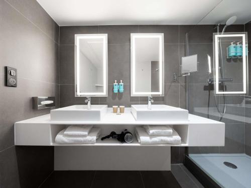 a bathroom with two sinks and two mirrors at Novotel Suites Montpellier Antigone in Montpellier