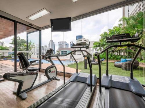 a gym with cardio equipment and a large window at Grand Mercure Bangkok Asoke Residence in Bangkok