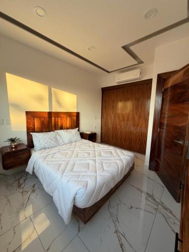 a bedroom with a large bed with a wooden headboard at Monbelt Luxury Apartment with Rooftop Jacuzzi in Puerto Vallarta