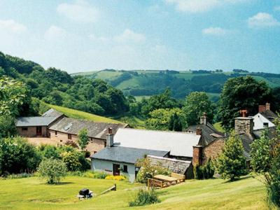 a group of houses in a green field with trees at Bracken Cottage-B5817 in Wheddon Cross