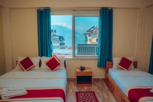 a room with two beds and a large window at Hotel KR Mandap in Pokhara