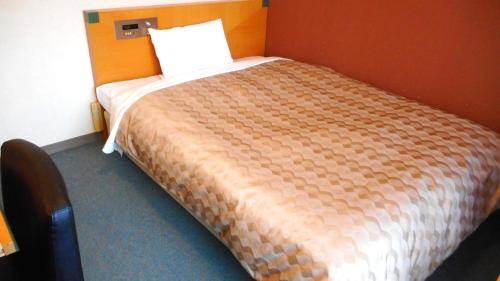 a bedroom with a large bed with a orange wall at Kuretake Inn Asahikawa in Asahikawa