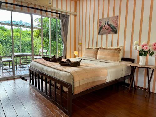 a bedroom with a large bed and a balcony at BAAN APA ERAWAN Resort in Ban Pong Pat