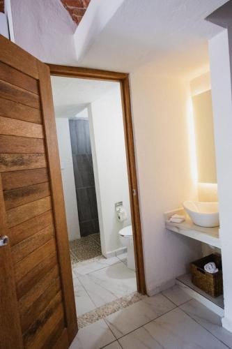 a bathroom with a toilet and a sink and a door at Paulas Suites Terraza in Ixtapa