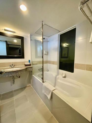 a white bathroom with a tub and a sink at Siam Piman Hotel in Bangkok