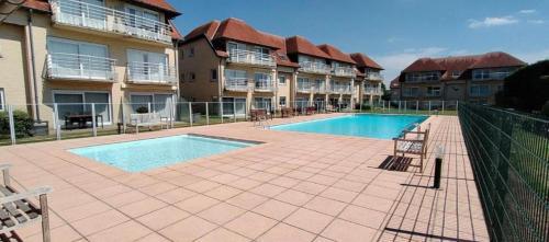 a swimming pool in front of some apartment buildings at Just like home De Haan aan Zee in De Haan