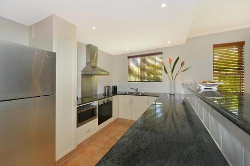 a kitchen with white cabinets and a black counter top at Cayman Villas Port Douglas in Port Douglas