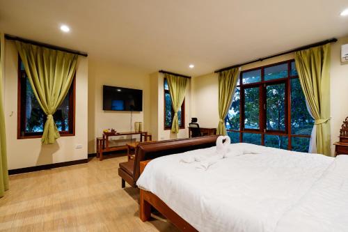 a bedroom with a large white bed and windows at Green Heaven Bungalows in Ban Bang Po