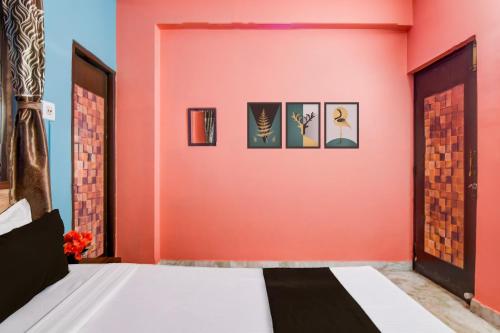 a bedroom with a pink wall with a bed at Super Hotel O Shalimar Railway Junction Howrah in Garden Reach