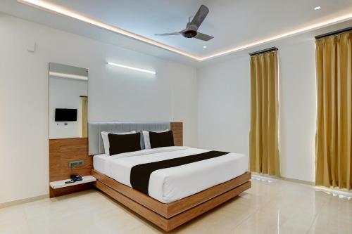 a bedroom with a large bed with a ceiling fan at Super Townhouse Oak T. Narasipura Road Formerly Hotel Nishara in Mysore
