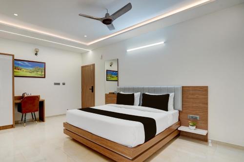 a bedroom with a large bed and a desk at Super Townhouse Oak T. Narasipura Road Formerly Hotel Nishara in Mysore