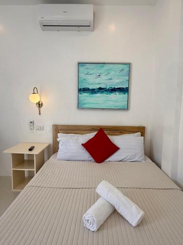 a bed with a red and white towel on it at Ivorys Guesthouse in Panglao Island