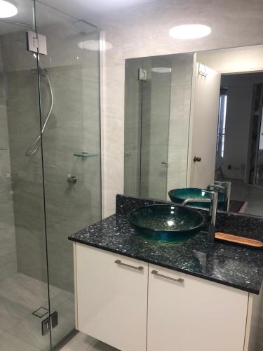 a bathroom with a sink and a glass shower at Cairns Apartment Esplanade Ocean Views in Cairns