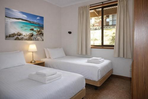 two beds in a room with a window at Bayview Cabins Kangaroo Island in American River