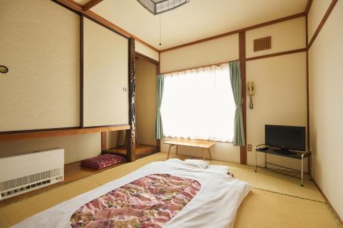 a bedroom with a large bed and a window at 旅館おぎた Ryokan Ogita - near Shiraoi Station in Shiraoi