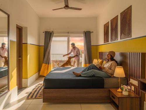 a woman sitting on a bed in a bedroom with a dog at The Hosteller Kodaikanal in Kodaikānāl