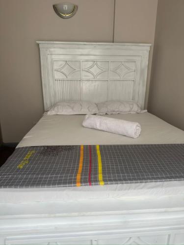 a white bed with a white headboard and two towels at Edwin homes in Nairobi