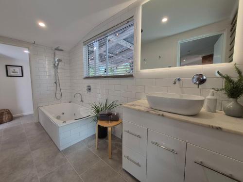 a bathroom with a tub and a sink and a bath tub at Finchy Cottage in Beechworth