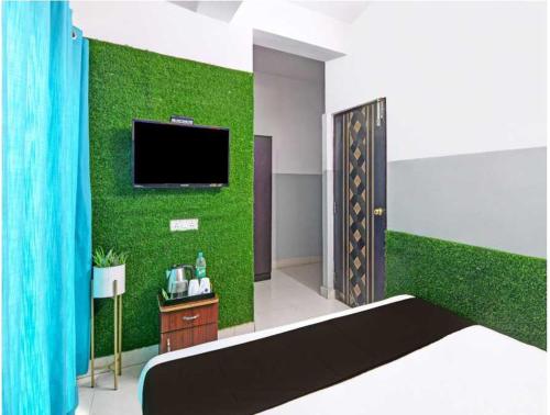 a bedroom with a green wall with a tv at Hotel O Krishna Bhawan in kolkata