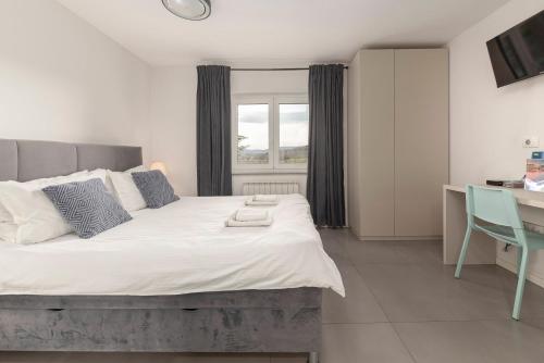 a bedroom with a large bed with a desk and a window at New Apartments Škofije Ankaran in Koper