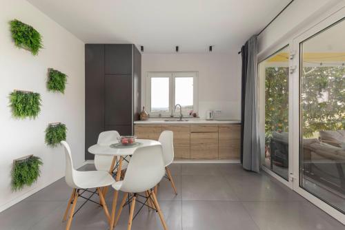 a kitchen with white chairs and a white table at New Apartments Škofije Ankaran in Koper