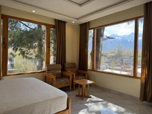 a bedroom with a bed and large windows with a view at Northlanders Guest House Skardu in Skardu