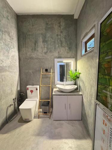 a bathroom with a sink and a toilet and a mirror at Villa Lithu in Weligama