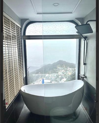a bath tub in a room with a large window at Time Villa in Tam Ðảo