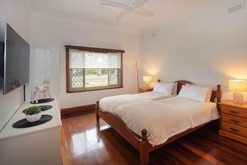 a white bedroom with a bed and a window at Busselton Central Accommodation in Busselton