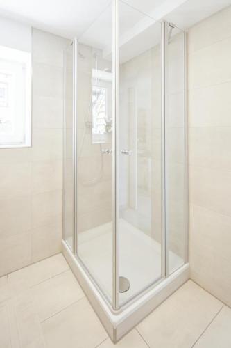 a glass shower in a bathroom with white tiles at Tiny Ferienwohnung am Stadtpark in Schwäbisch Hall