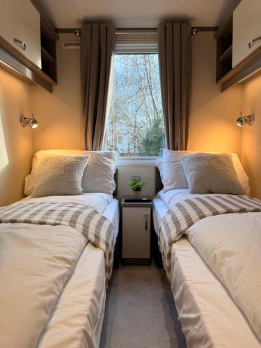 two beds in a small room with a window at Archerfield Luxe Lodge in Port Seton