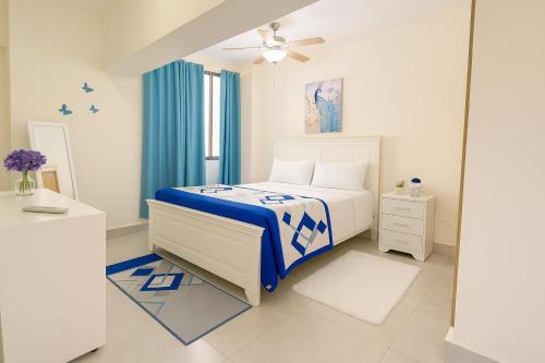 a white bedroom with a blue and white bed and a window at Boca del mar III in Boca Chica