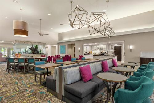 a lobby with a couch and tables and chairs at Homewood Suites Fort Myers Airport - FGCU in Fort Myers