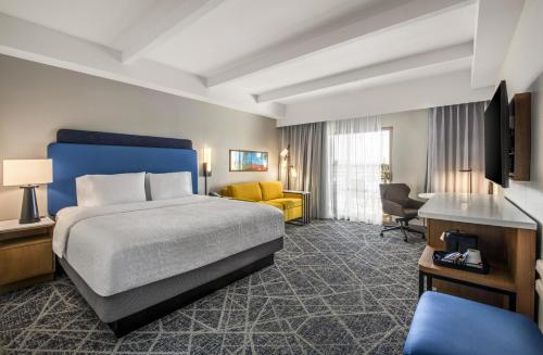 a hotel room with a bed and a yellow couch at Hampton Inn Channel Islands Harbor in Oxnard