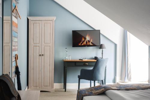 a bedroom with a desk with a fireplace on the wall at Kleinhuis Hotel Mellingburger Schleuse in Hamburg