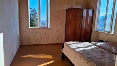 a bedroom with a bed and two windows at სახლი ბუნებაში House in nature in Ts'ikhisdziri