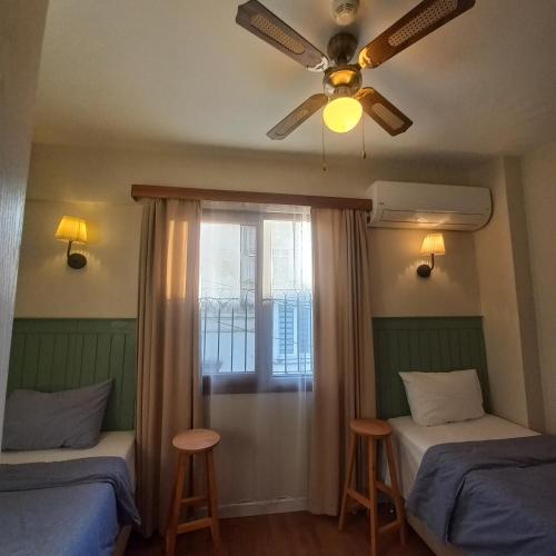 a bedroom with two beds and a ceiling fan at Dalgaci Deniz Konukevi in Ayvalık