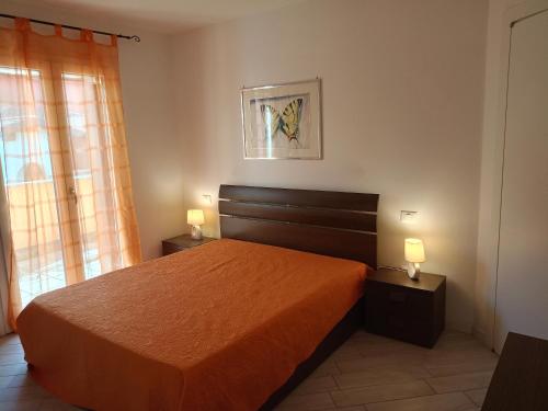 a bedroom with a bed with orange sheets and two lamps at Corte DON BOSCO 5 in Monfalcone