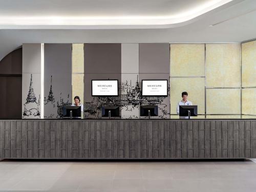 two people sitting at a reception desk in a lobby at Mercure Bangkok Siam in Bangkok