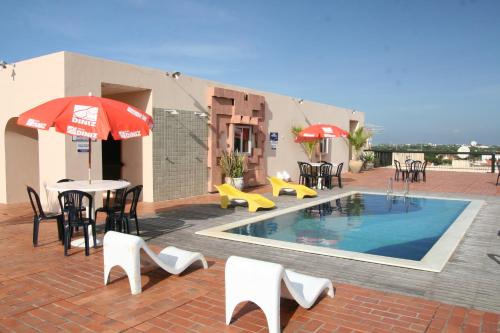 a patio with a pool and tables and chairs at Hotel Delta in Parnaíba
