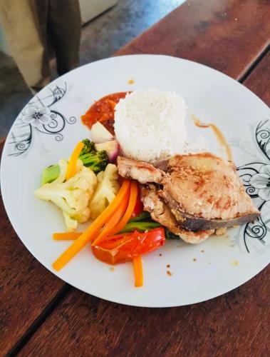 une assiette de nourriture avec du riz et des légumes sur une table dans l'établissement Paje lounge, à Paje