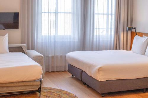 a hotel room with two beds and a chair at Hotel Arena in Amsterdam