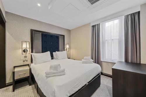 a hotel room with a large bed with white sheets at The Westbourne Residences in London