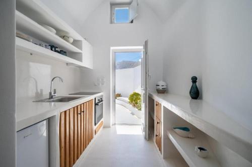 a kitchen with white counters and a door to a balcony at Fertimo Suites - Authentic Cave Homes with Private Hot Tub in Éxo Goniá