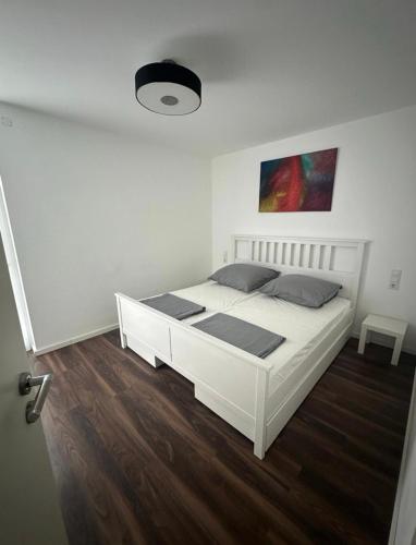 Ein weißes Bett in einem weißen Schlafzimmer mit Holzboden in der Unterkunft Apart Halver in Halver